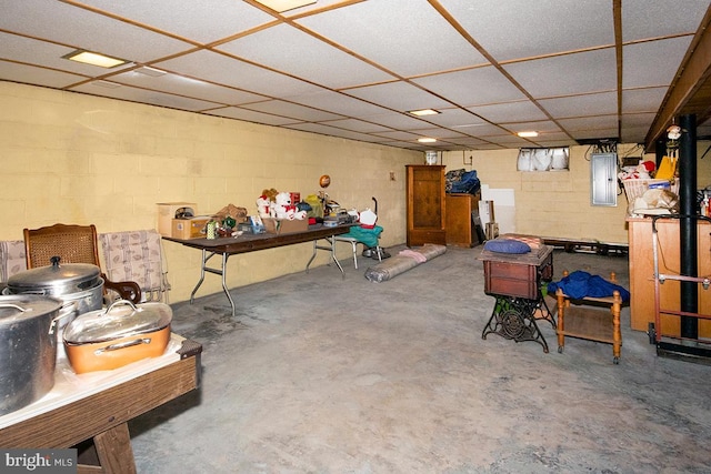 basement with a drop ceiling and electric panel