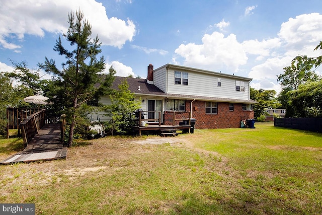 rear view of property with a deck and a lawn