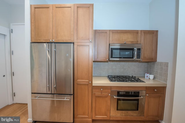 kitchen featuring stainless steel appliances, light hardwood / wood-style floors, and decorative backsplash