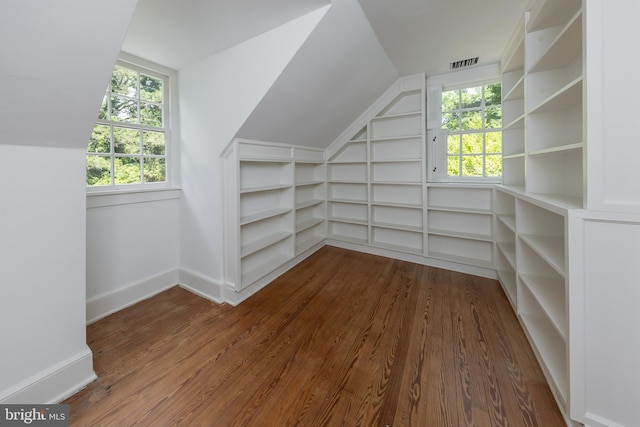 additional living space with built in shelves, wood-type flooring, and lofted ceiling