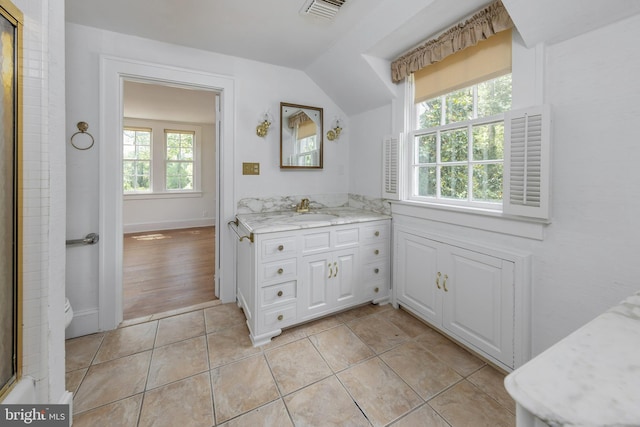 bathroom with tile patterned flooring, vanity, and vaulted ceiling