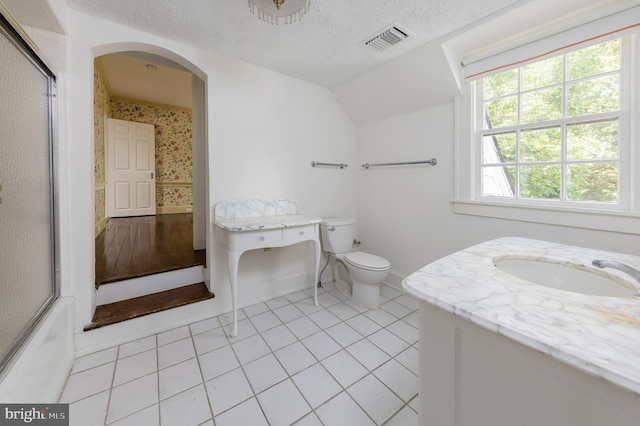 full bathroom featuring vanity, shower / bath combination with glass door, tile patterned flooring, toilet, and a textured ceiling