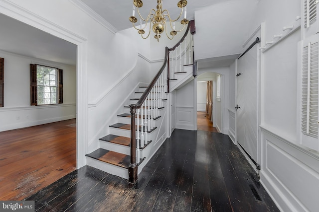 stairs with crown molding, hardwood / wood-style floors, and a notable chandelier