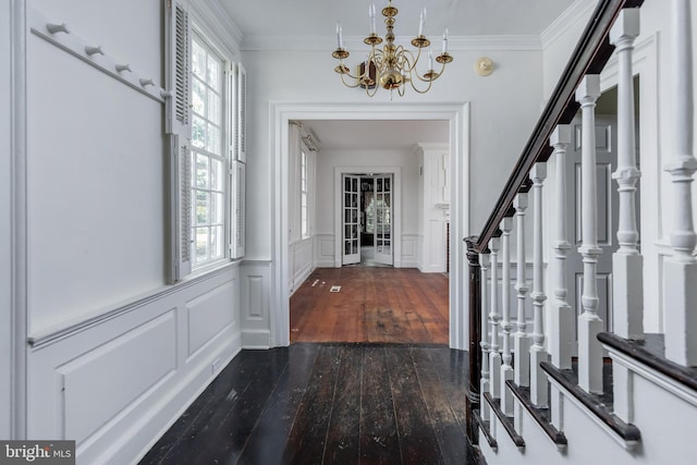 foyer featuring an inviting chandelier, crown molding, and dark wood-type flooring