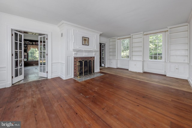 unfurnished living room featuring french doors, dark hardwood / wood-style flooring, a brick fireplace, and crown molding