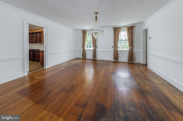 empty room with dark hardwood / wood-style flooring, an inviting chandelier, and crown molding