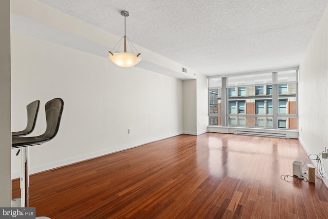 unfurnished living room featuring wood-type flooring, a textured ceiling, a baseboard radiator, and expansive windows