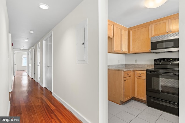 kitchen featuring light stone countertops, light brown cabinetry, electric range, and electric panel