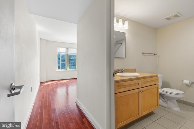 bathroom with hardwood / wood-style floors, vanity, and toilet