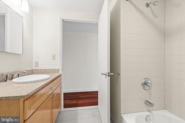 bathroom featuring tile patterned flooring, tiled shower / bath combo, and vanity