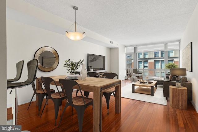 dining room featuring floor to ceiling windows, a textured ceiling, and hardwood / wood-style flooring