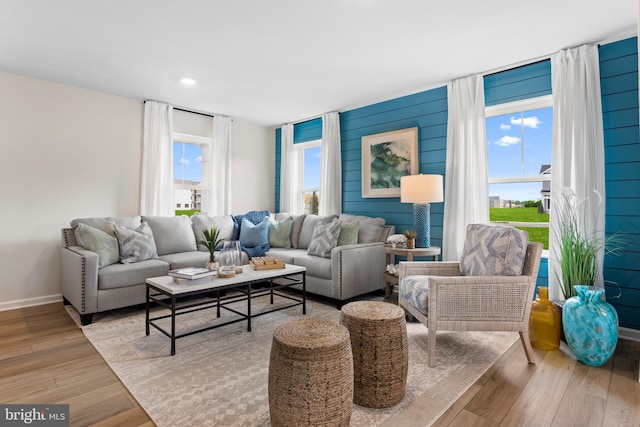 living room featuring wood walls, a healthy amount of sunlight, and light hardwood / wood-style flooring