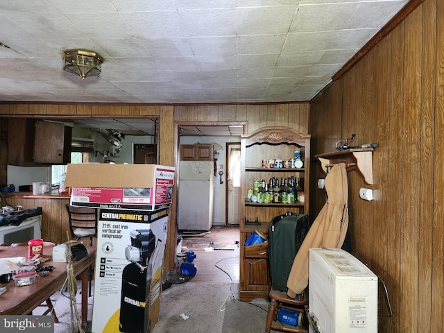 interior space featuring white fridge, wood walls, and concrete floors