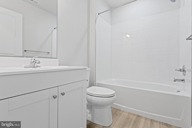 full bathroom with hardwood / wood-style flooring, toilet, tiled shower / bath combo, and vanity