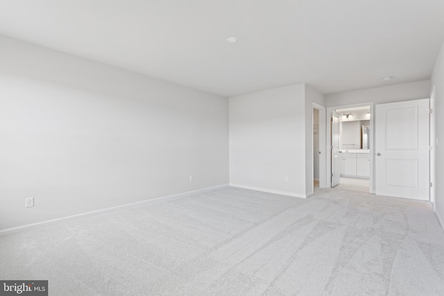 unfurnished bedroom featuring ensuite bathroom, light carpet, a closet, and a walk in closet