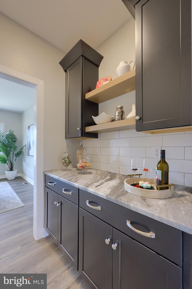 kitchen with light stone countertops, light hardwood / wood-style floors, and decorative backsplash