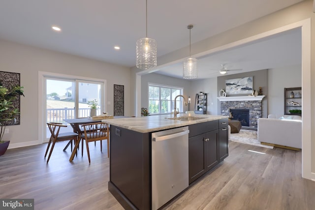 kitchen with sink, hanging light fixtures, a center island with sink, light wood-type flooring, and dishwasher