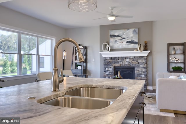 kitchen with a stone fireplace, light stone countertops, sink, and a wealth of natural light