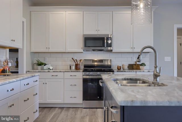 kitchen featuring sink, backsplash, white cabinets, and appliances with stainless steel finishes