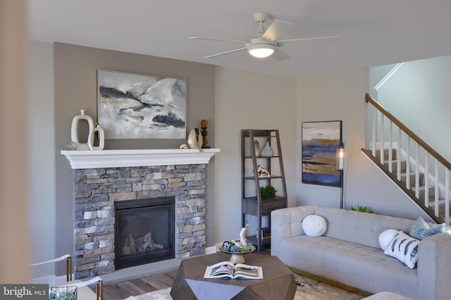 living room featuring ceiling fan, a fireplace, and light hardwood / wood-style floors