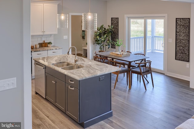 kitchen featuring sink, white cabinets, a kitchen island with sink, stainless steel dishwasher, and light hardwood / wood-style flooring