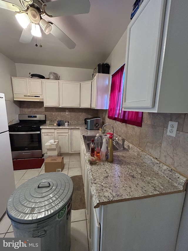 kitchen featuring white cabinets, sink, stainless steel range oven, and light tile patterned flooring