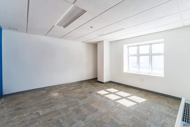 carpeted empty room with a drop ceiling