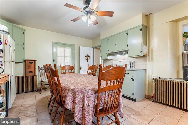 tiled dining space with radiator heating unit and ceiling fan