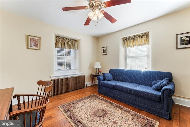 living room featuring wood-type flooring, ceiling fan, and radiator