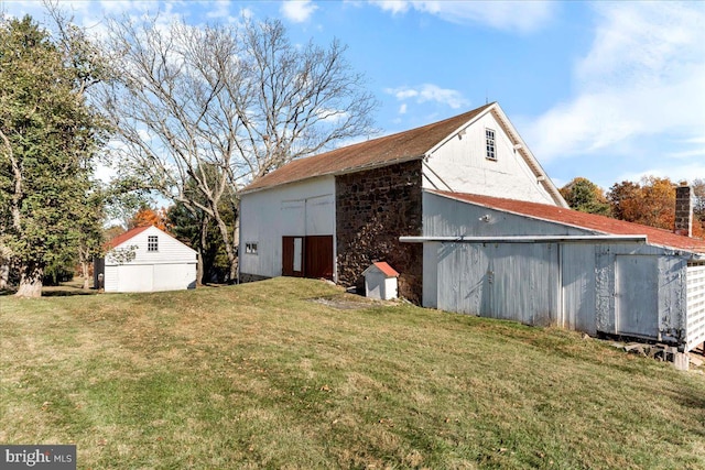 view of home's exterior with a lawn and an outdoor structure