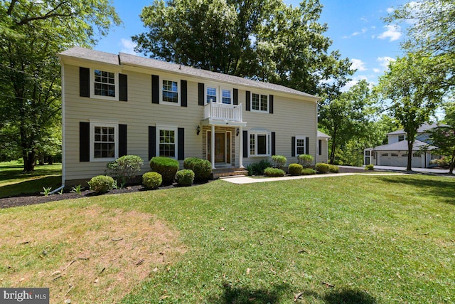 colonial home with a garage, a balcony, and a front lawn