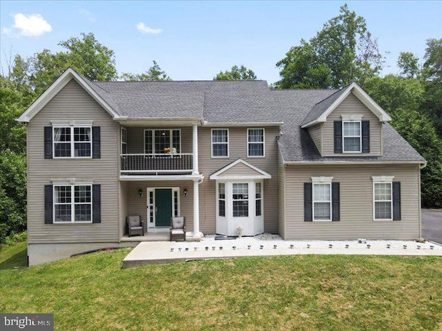 view of front of house with a balcony and a front yard