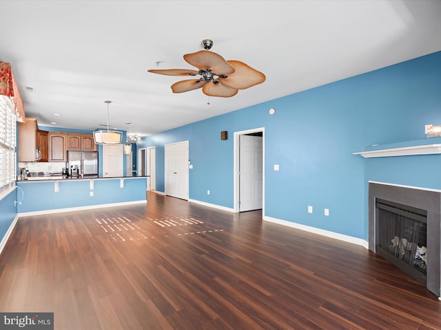 unfurnished living room with ceiling fan and dark wood-type flooring