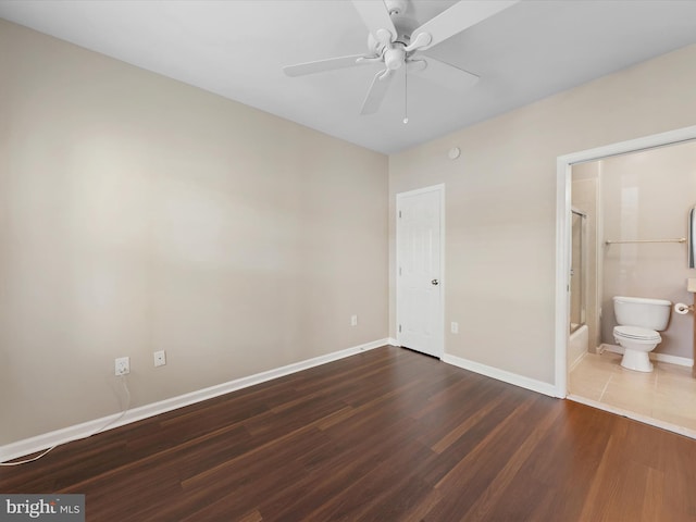 unfurnished bedroom with ensuite bath, ceiling fan, and dark hardwood / wood-style floors