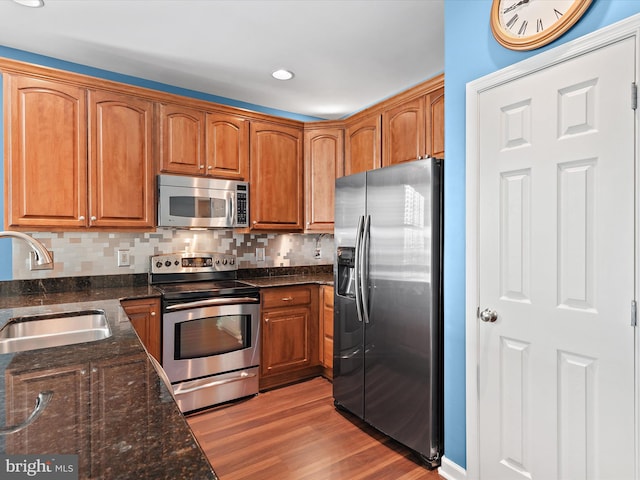 kitchen with decorative backsplash, sink, stainless steel appliances, and light hardwood / wood-style flooring