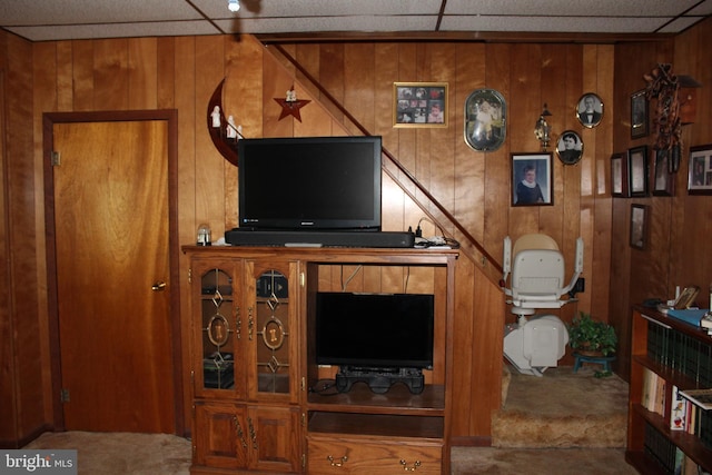 living room with a paneled ceiling and wooden walls