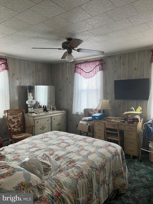 bedroom with dark carpet, ceiling fan, and wooden walls