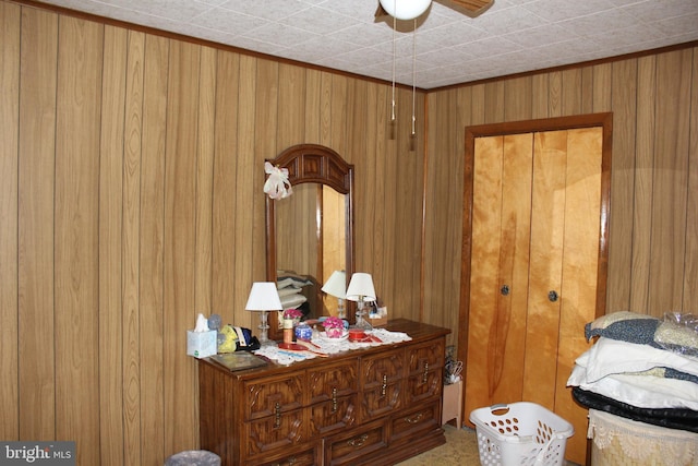 bedroom with a closet, wooden walls, and ceiling fan