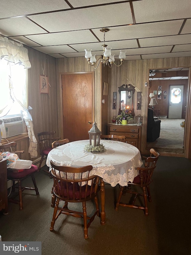 dining area featuring carpet flooring, cooling unit, wooden walls, and an inviting chandelier