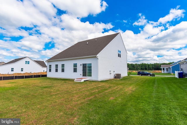 back of property featuring central air condition unit and a yard