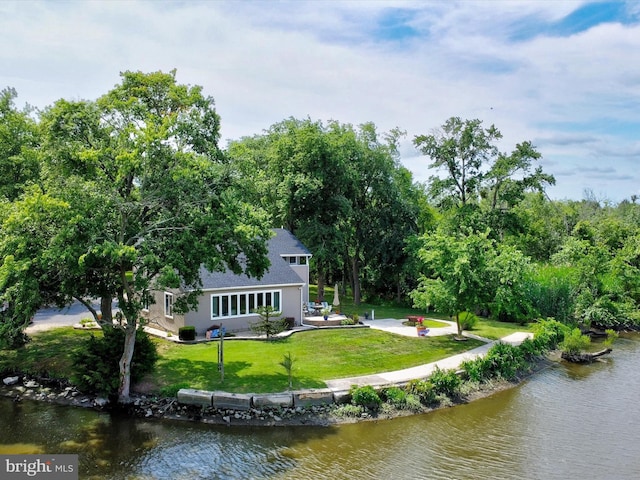 rear view of property featuring a water view, a patio, and a lawn