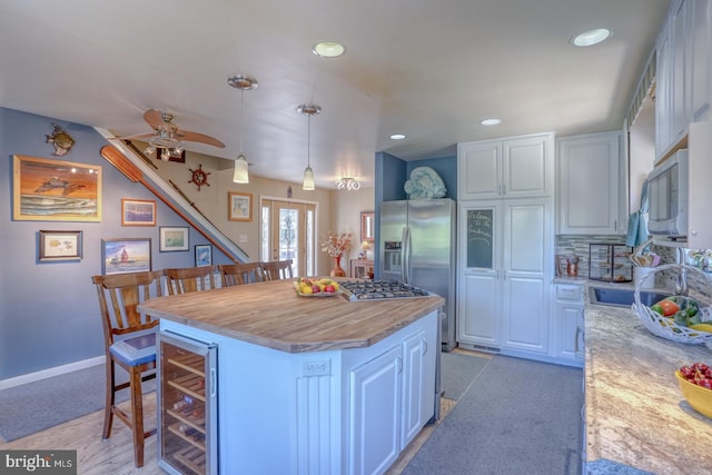 kitchen featuring appliances with stainless steel finishes, white cabinetry, a kitchen breakfast bar, hanging light fixtures, and a center island