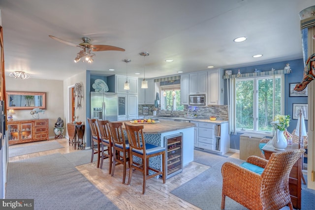 kitchen with decorative light fixtures, plenty of natural light, a kitchen island, stainless steel appliances, and backsplash