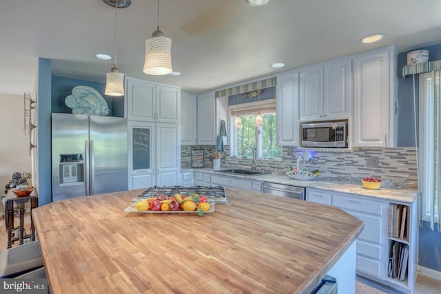 kitchen with pendant lighting, sink, appliances with stainless steel finishes, backsplash, and a kitchen island