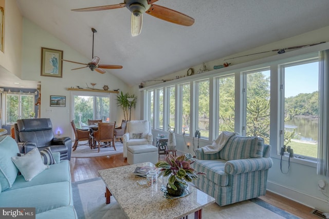 sunroom / solarium featuring a water view, lofted ceiling, and ceiling fan