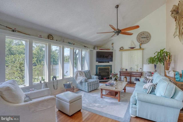 living room with lofted ceiling, a tile fireplace, a textured ceiling, and light wood-type flooring