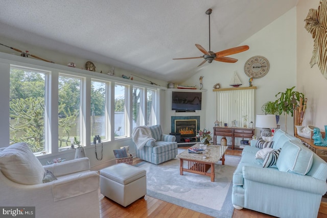 living room with ceiling fan, lofted ceiling, light hardwood / wood-style flooring, and a textured ceiling