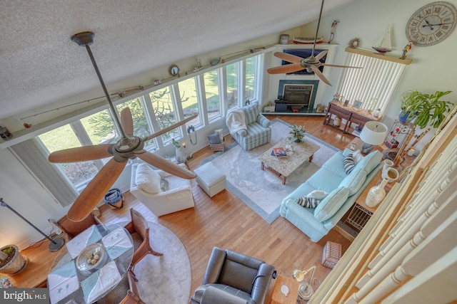 living room featuring hardwood / wood-style flooring, lofted ceiling, a textured ceiling, and ceiling fan