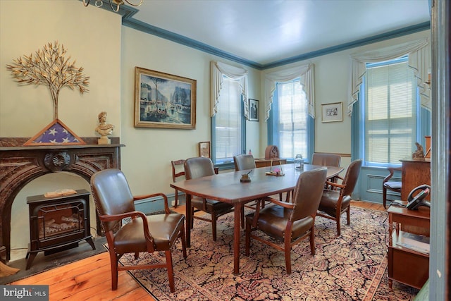 dining room featuring light hardwood / wood-style floors, a wood stove, a wealth of natural light, and crown molding