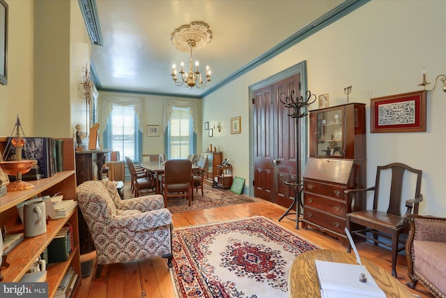 sitting room with crown molding, light hardwood / wood-style flooring, and a chandelier